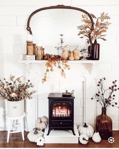 the fireplace is decorated with pumpkins, candles and other autumn decorating items on it