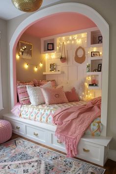 a bedroom with pink walls and lights on the headboard is decorated in white, pink and gold