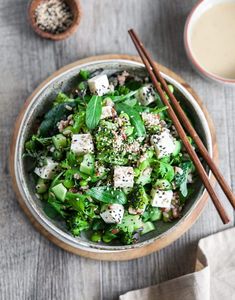 a bowl filled with salad next to two chopsticks