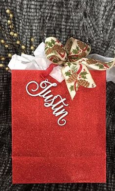 a red gift bag with the word happy on it and a bow tied to it