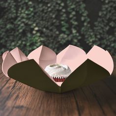 an origami cupcake in a box on a wooden table with trees in the background