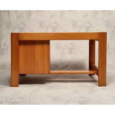 a wooden table sitting on top of a white floor next to a gray wall in front of it