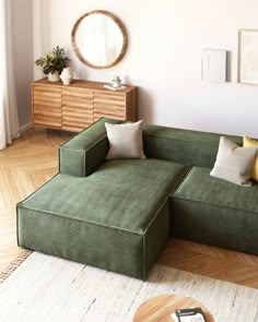 a green couch sitting on top of a hard wood floor next to a wooden table