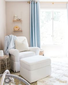 a white chair and ottoman in front of a window with blue drapes on the windowsill