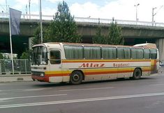 an old bus is parked on the side of the road in front of a bridge