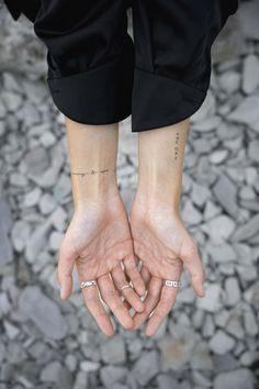 two hands holding each other with small tattoos on them