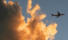 an airplane is flying in the sky with some clouds behind it at sunset or dawn