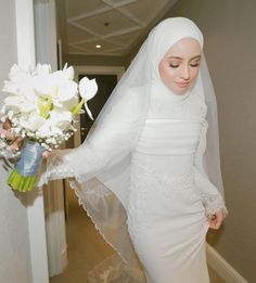 a woman in a white wedding dress holding a bouquet of flowers and wearing a veil