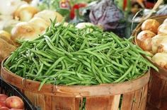 several baskets filled with green beans and onions next to each other in front of a store window