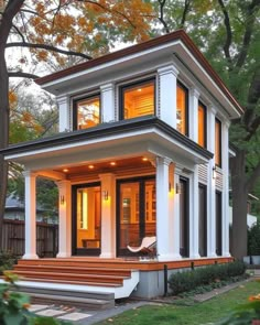 a small white house with lots of windows and steps leading up to the front door