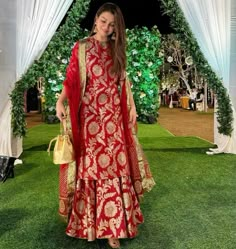 a woman in a red and gold outfit standing under an arch with white drapes