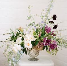 a vase filled with lots of flowers sitting on top of a table