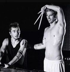 two shirtless men standing next to each other holding baseball bats in their hands and looking at the camera