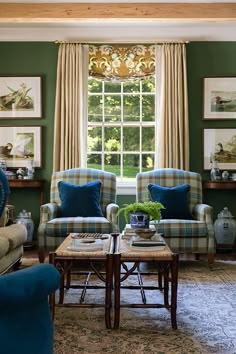 a living room with green walls and blue chairs in front of a window filled with pictures