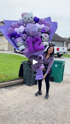 a woman standing in front of a trash can holding a large bouquet of stuffed animals