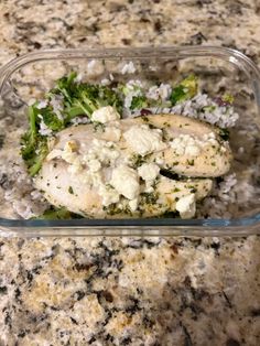 a plastic container filled with chicken and broccoli on top of a granite counter