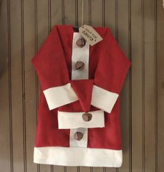 a red and white santa suit hanging on a wall