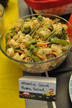 a glass bowl filled with pasta salad on top of a table next to other plates