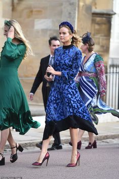 two women walking down the street in dresses and high heeled shoes, one wearing a blue floral print dress