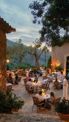 an outdoor dining area with tables, chairs and people sitting at the table eating outside