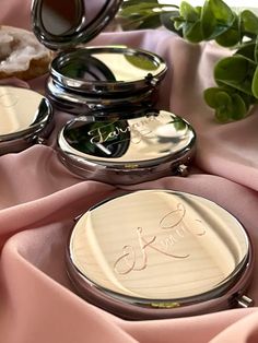 three compact mirrors sitting on top of a pink cloth