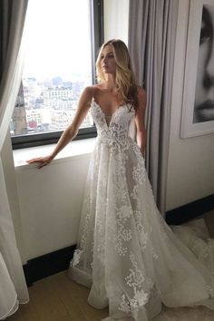 a woman standing in front of a window wearing a wedding dress