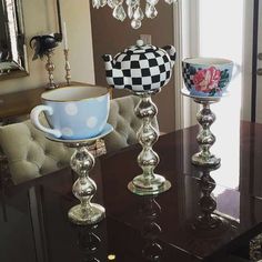 a dining room table with two tea cups on it and a vase in the middle