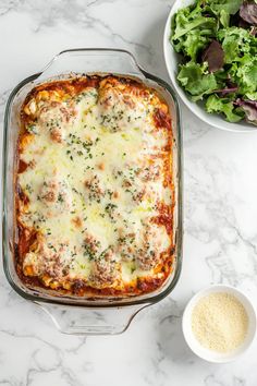 a casserole dish with meat and cheese in it next to a bowl of salad