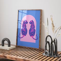 two cats sitting on their hind legs in front of a blue and pink background, framed by wood slats