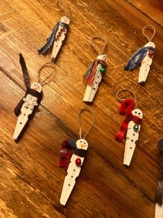 several ornaments made to look like snowmen hanging from strings on a wooden table top