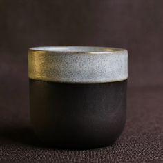 a black and white bowl sitting on top of a brown cloth covered floor next to a wall