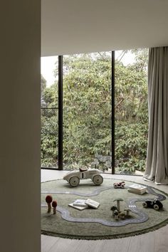 a round rug in the middle of a room with lots of windows and toys on the floor