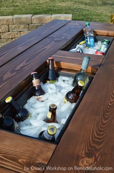 an outdoor table with ice and beer bottles in it