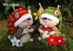 three stuffed animals wearing knitted hats and scarfs sitting in the grass next to a tree