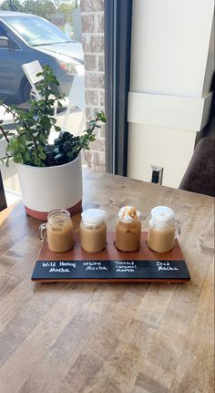 there are three cups on the table with some ice cream in front of them and a potted plant next to it