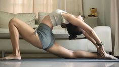 a woman is doing yoga on the floor in front of a couch with her legs spread out