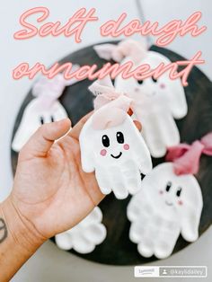 someone is holding out their hand to show off some fake ghost finger puppets that are on top of the cake