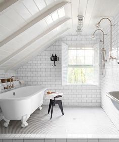 an attic bathroom with white brick walls and flooring, along with a claw foot tub