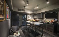 a kitchen with gray cabinets and white counter tops is pictured in this image, there are two bar stools at the center of the island