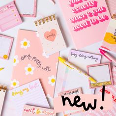 many different types of notepads and pens on a white surface with pink writing