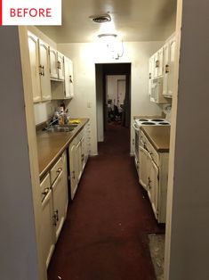 an empty galley kitchen with white cabinets and red carpeted flooring is seen in this image