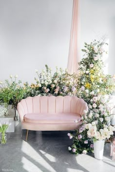 a pink couch sitting next to flowers and plants