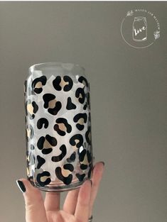 a person holding up a glass with leopard print on it