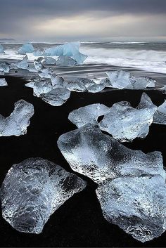 icebergs floating in the water on black sand beach with dark clouds above them