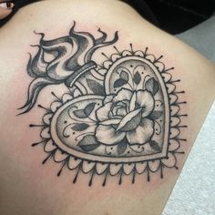 a black and white heart tattoo on the back of a woman's shoulder