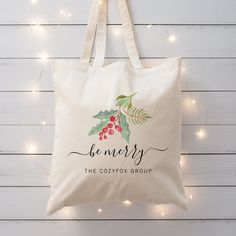 a tote bag with holly and berries on it hanging from a string of lights