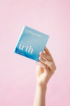 a person holding up a box of toothpaste against a pink background with the word truth written on it