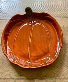 a ceramic pumpkin shaped dish on a wooden table