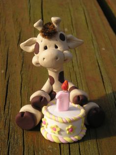 a giraffe figurine sitting next to a birthday cake on a wooden table