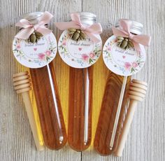 three honey bottles with labels on them sitting next to some wooden utensils